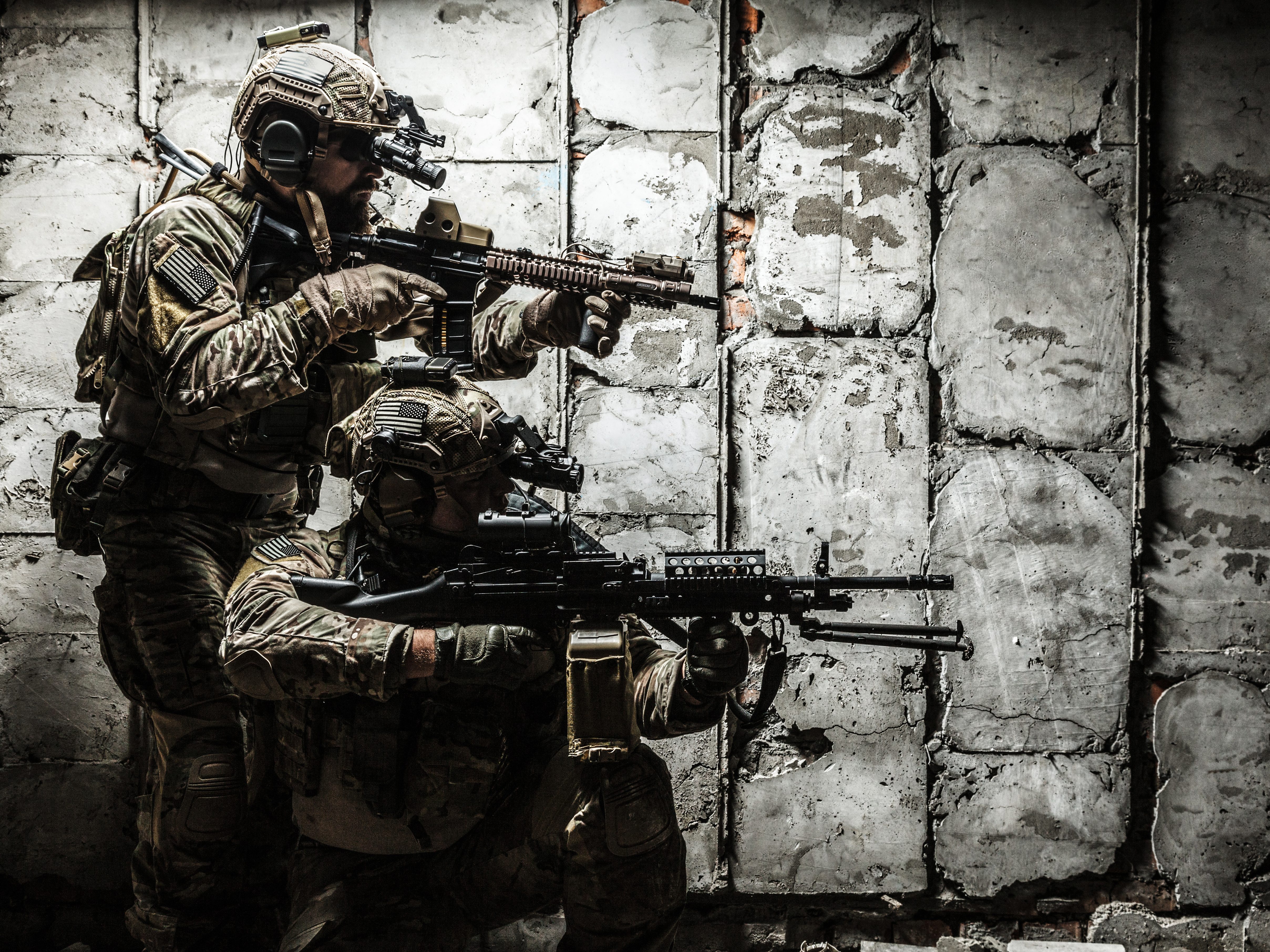 Two U.S. soldiers in full combat gear aiming rifles inside a damaged building, representing the need for dependable, high-performance military-grade ammunition in urban operations.